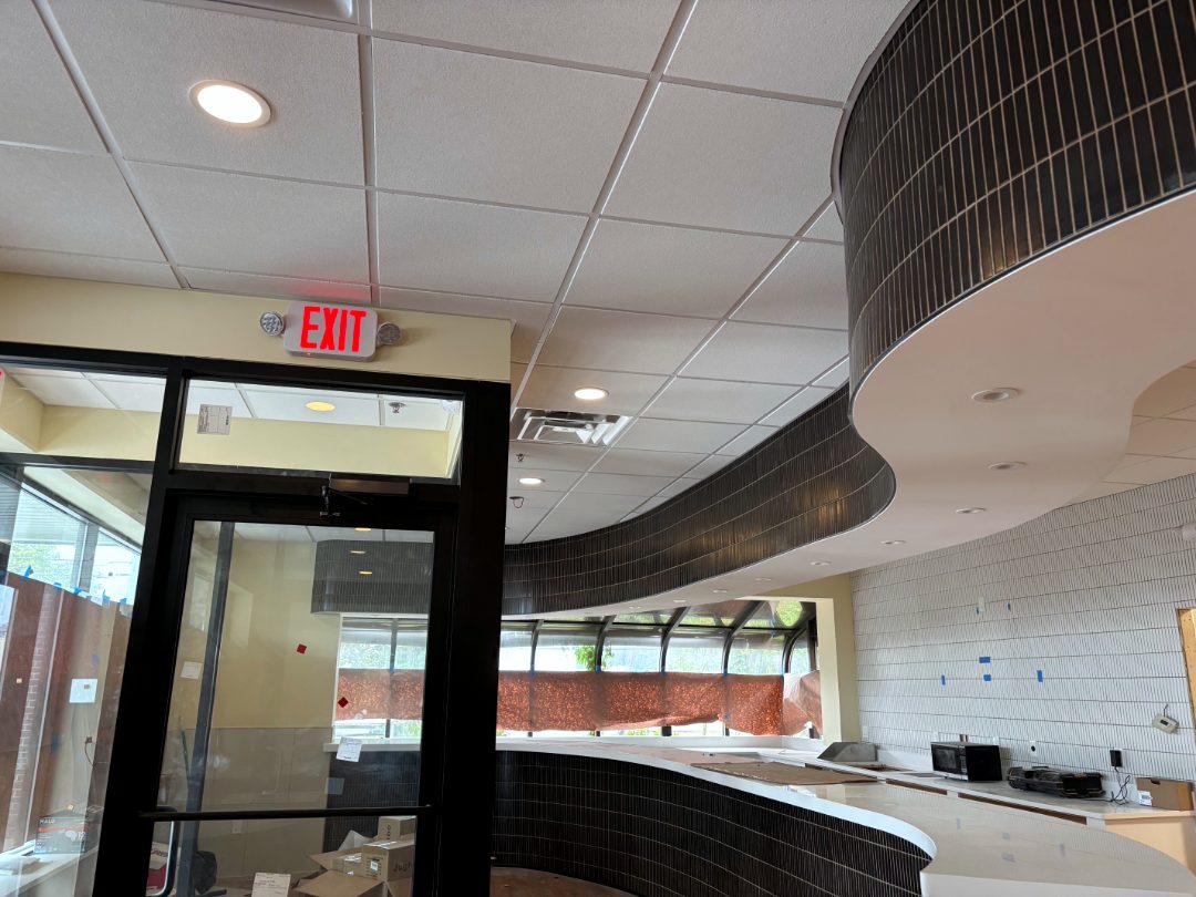 Grid ceiling fitted around a curved dark tile soffit in a restaurant